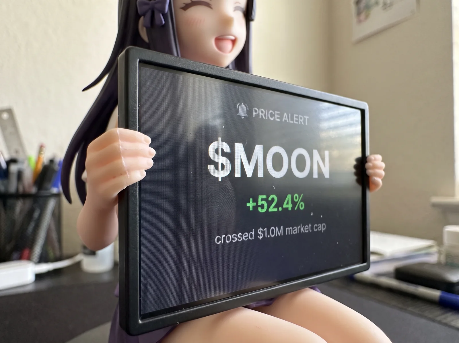 Close-up of the screen in her hands showing a price alert for $MOON